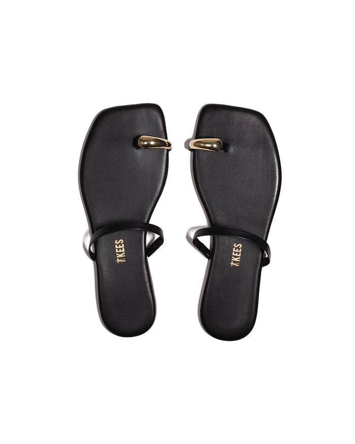 Top-down view of both black TKEES Colette Sandals with gold dome toe hardware.