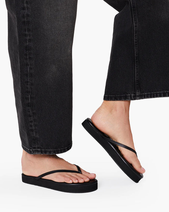 Side view of a model wearing the black TKEES Lily Platform Sandals with dark jeans.