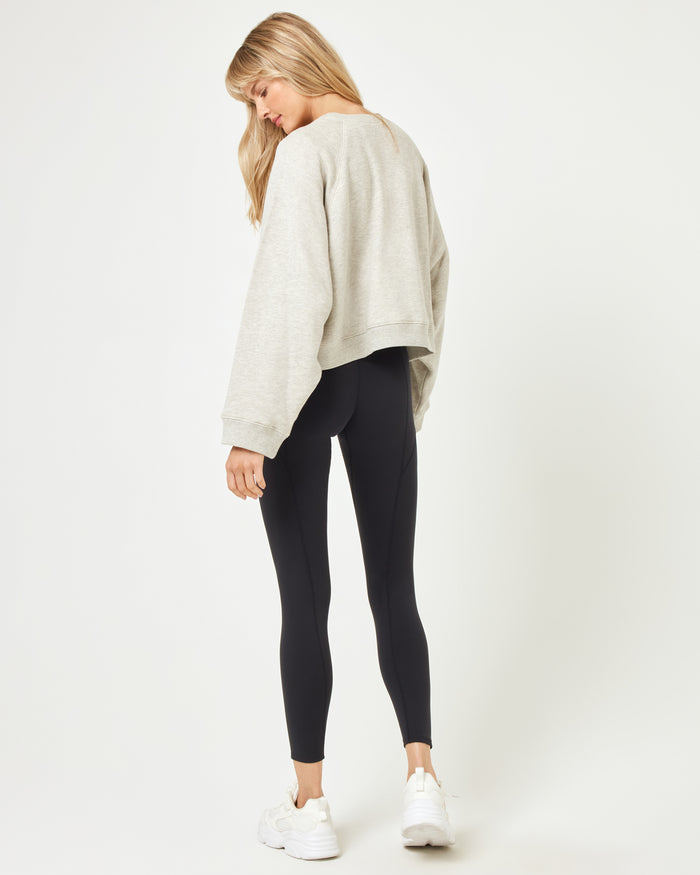 Back view of model wearing the Vincent Pullover in heather grey with black shorts.