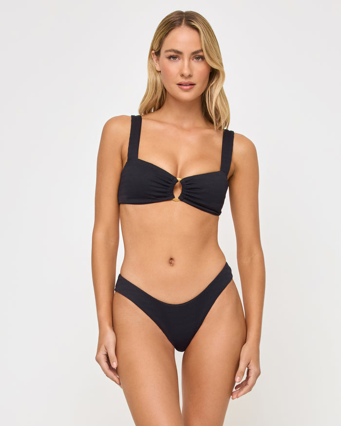 Front view of a model wearing the LSPACE Willow Bikini Top in black, featuring wide straps and a center front O-ring hardware detail, paired with the black Rocky Bikini Bottom.