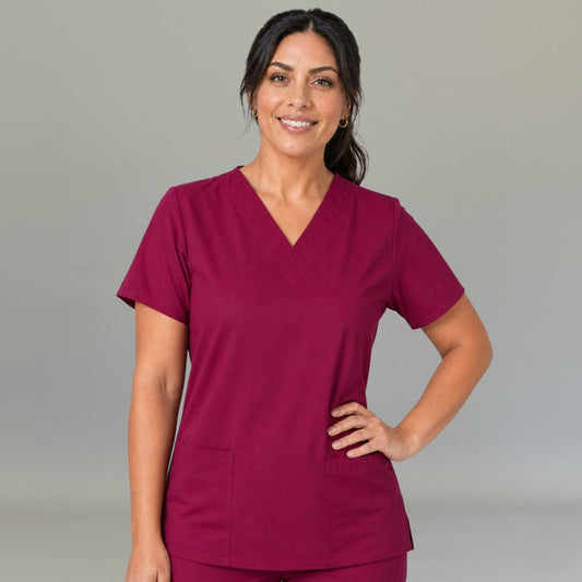 Women's FW 502 Fuchsia scrub top, front three-quarter view with one hand on the hip