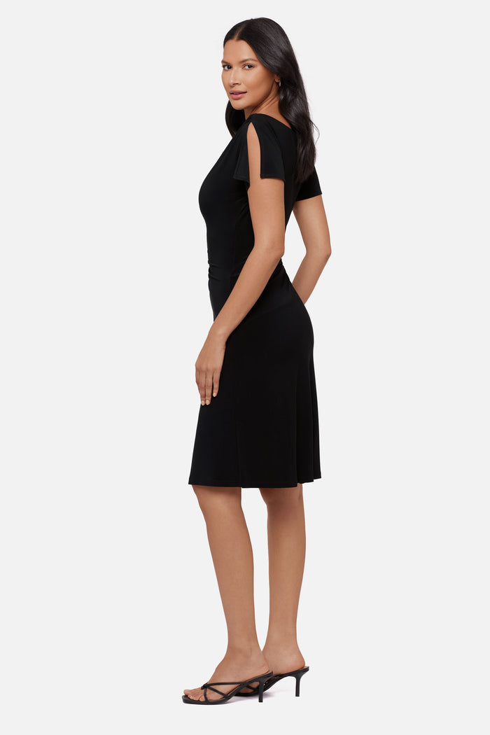 Woman faced left wearing a black slitted short sleeve mid length dress