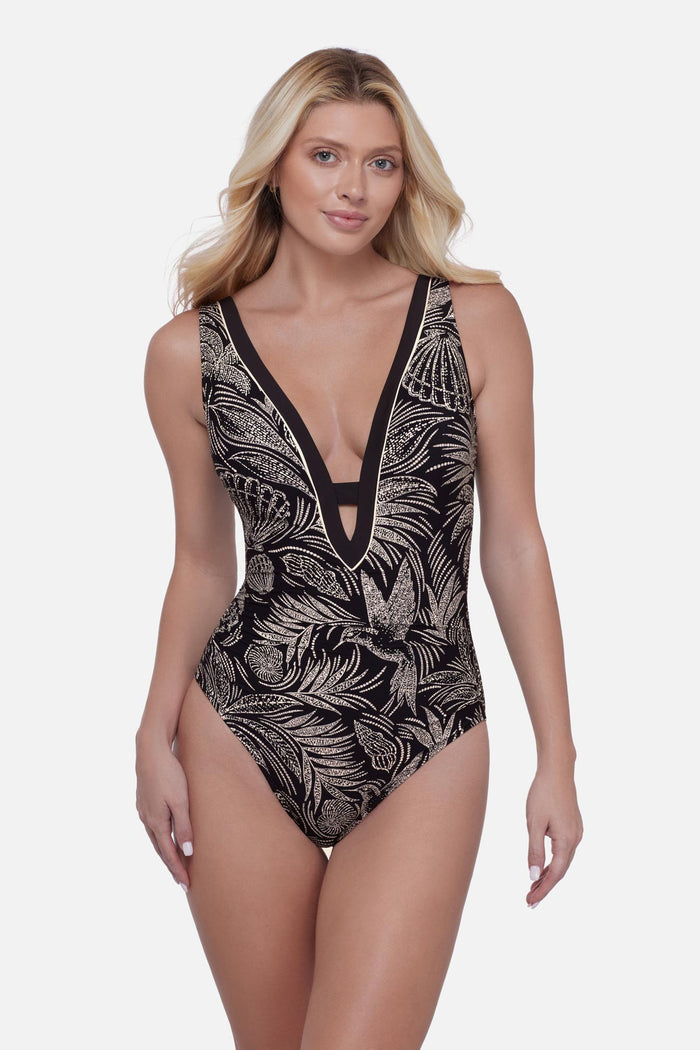 Woman wearing a black and white bird and leaf printed one-piece swimsuit with a deep V neckline