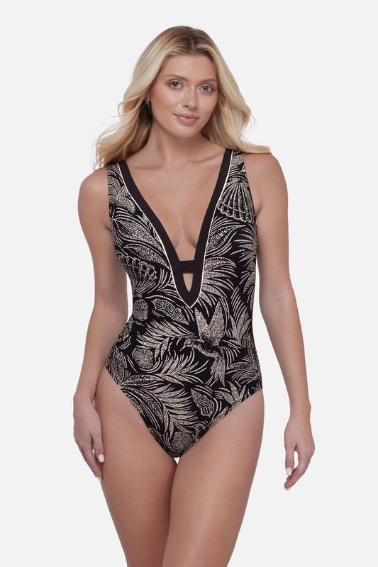 Woman wearing a black and white bird and leaf printed one-piece swimsuit with a deep V neckline