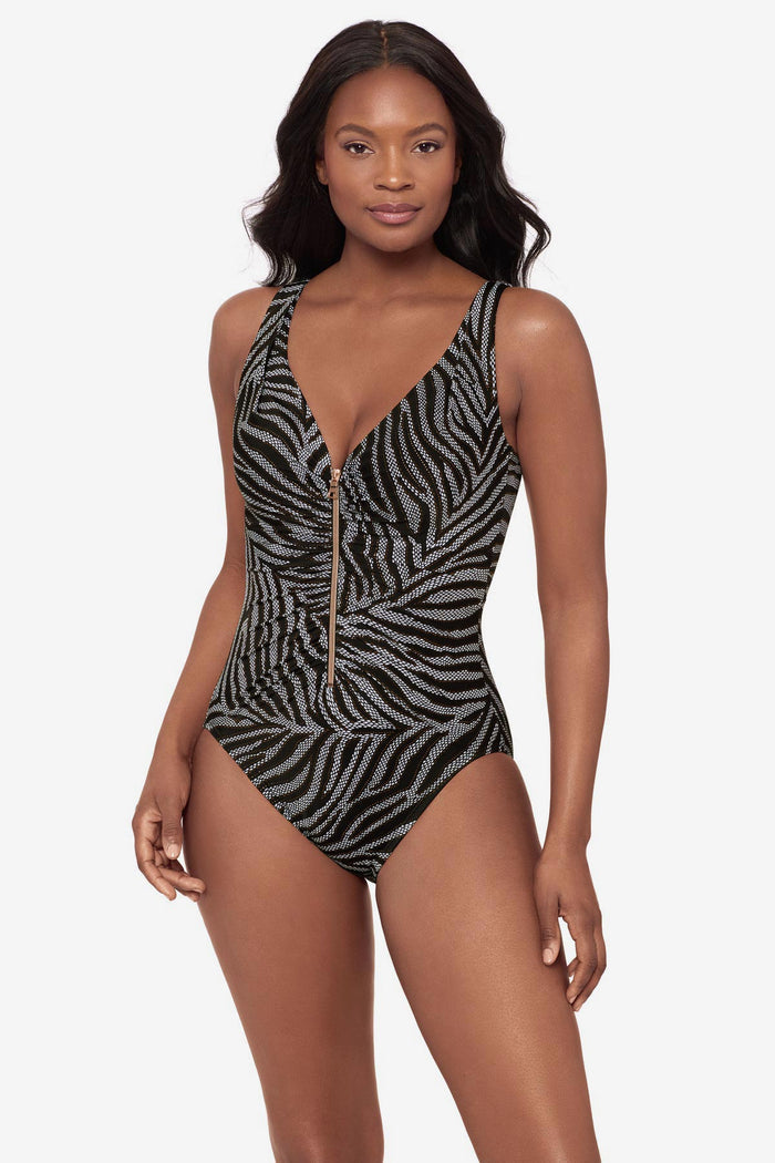 Woman wearing a black and white animal print-esque one-piece swimsuit with a zipper down the front