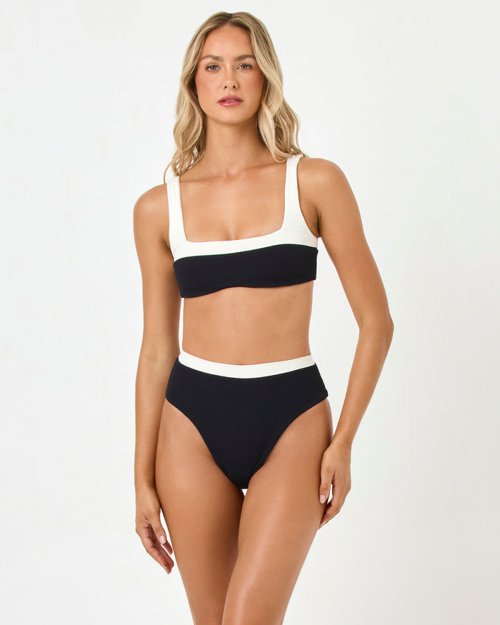 Front view of a model wearing the LSPACE black-cream Zuri Bikini Top with square neckline and matching Misha Bikini Bottom.